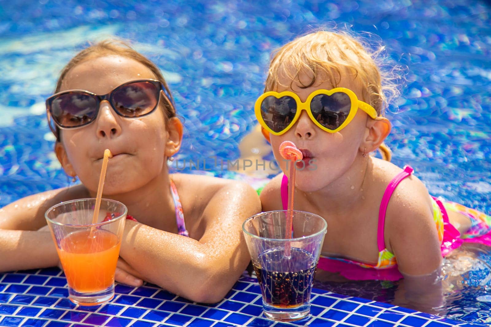 Children drink a cocktail in the pool. Selective focus. by yanadjana