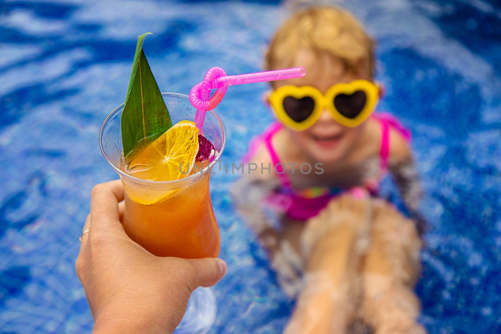 A woman in the pool drinks a cocktail. Selective focus. Travel.