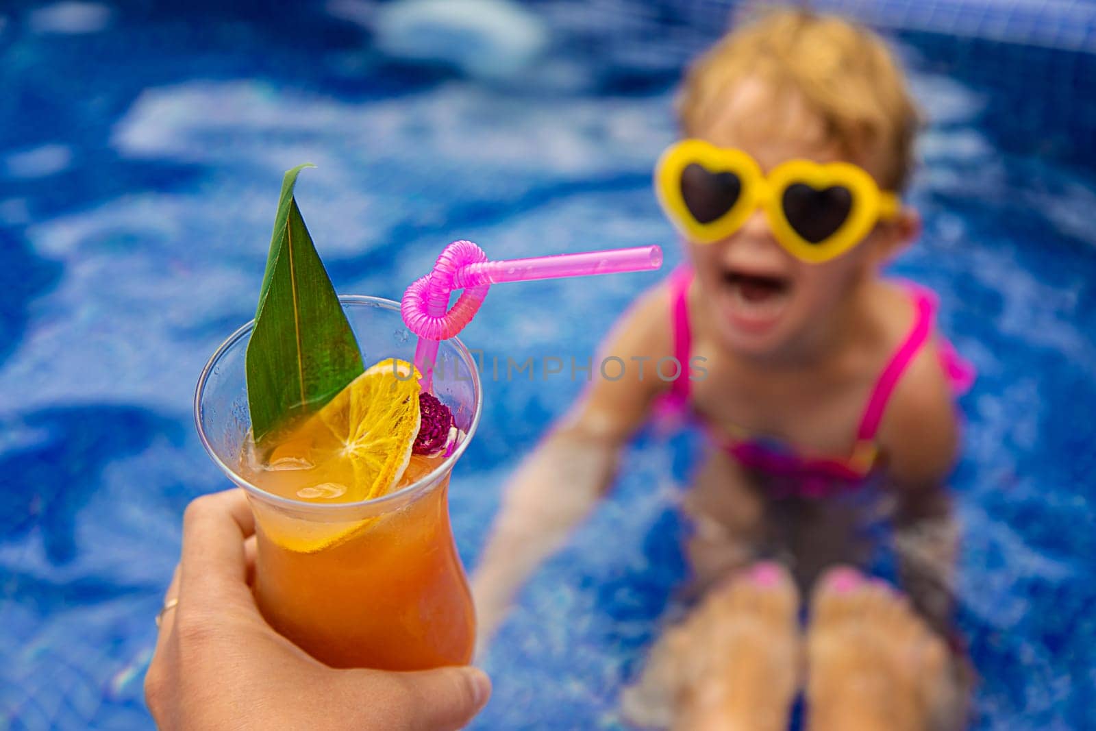 A woman in the pool drinks a cocktail. Selective focus. by yanadjana