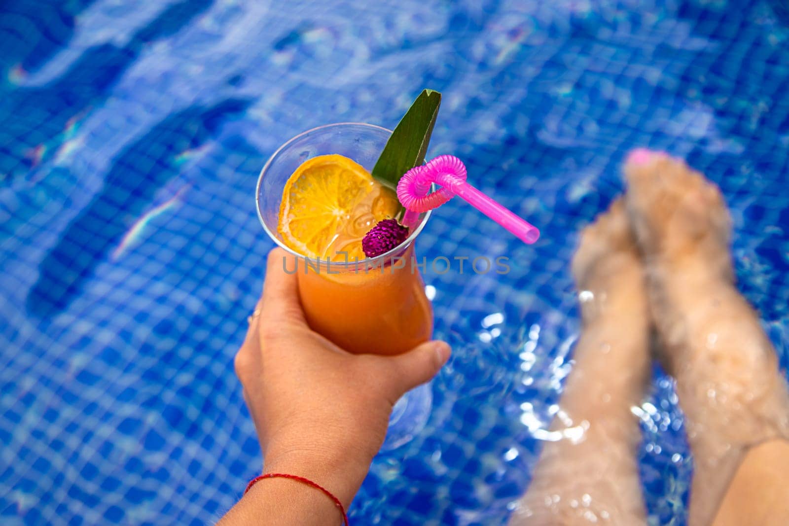 A woman in the pool drinks a cocktail. Selective focus. by yanadjana