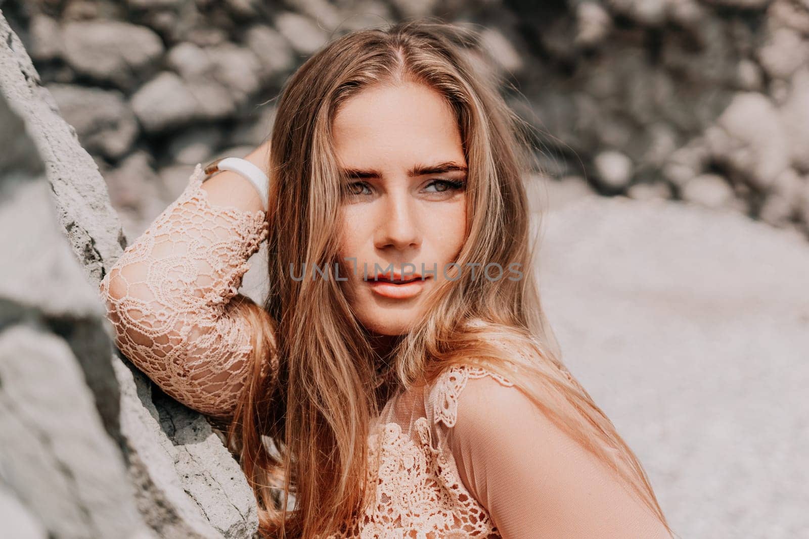 Woman summer travel sea. Happy tourist in beige dress enjoy taking picture outdoors for memories. Woman traveler posing on the beach surrounded by volcanic mountains, sharing travel adventure journey by panophotograph