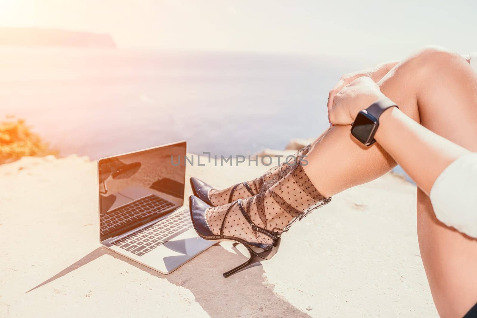 Woman sea laptop. Business woman in yellow hat freelancer with laptop working over blue sea beach. Girl relieves stress from work. Freelance, digital nomad, travel and holidays concept by panophotograph