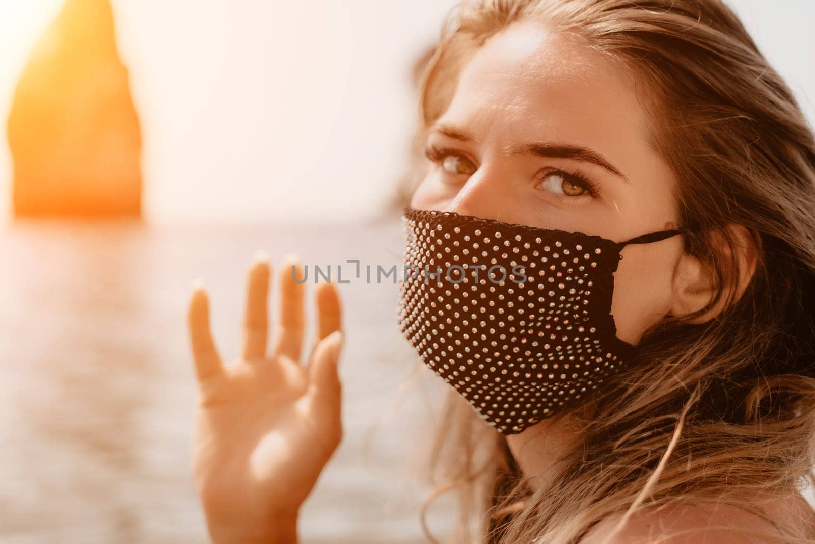 Woman summer travel sea. Happy tourist in black mask enjoy taking picture outdoors for memories. Woman traveler posing on the beach at sea surrounded by volcanic mountains, sharing travel adventure by panophotograph