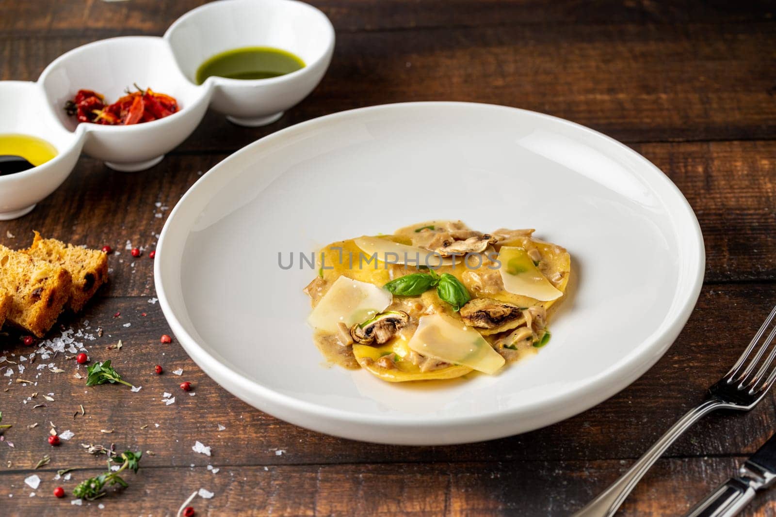 Italian dish ravioli with mushrooms and parmesan on wooden table by Sonat