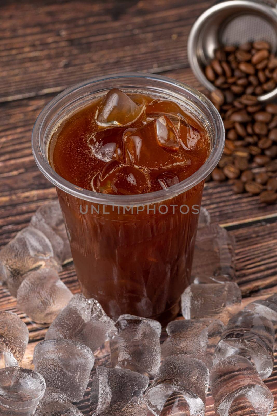 A cup of Iced Americano Coffee with ice cubes placed on a wooden table in a coffee shop. Top view of a glass of coffee. by Sonat