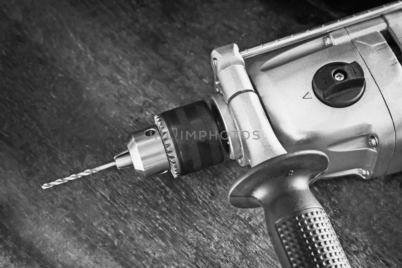 On a carpenter's workbench lies a compact electric hand drill.