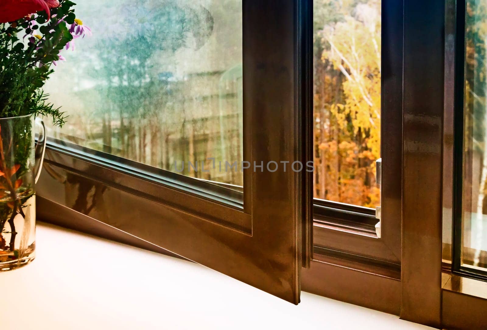 Open window with brown frames and views of autumn landscape.