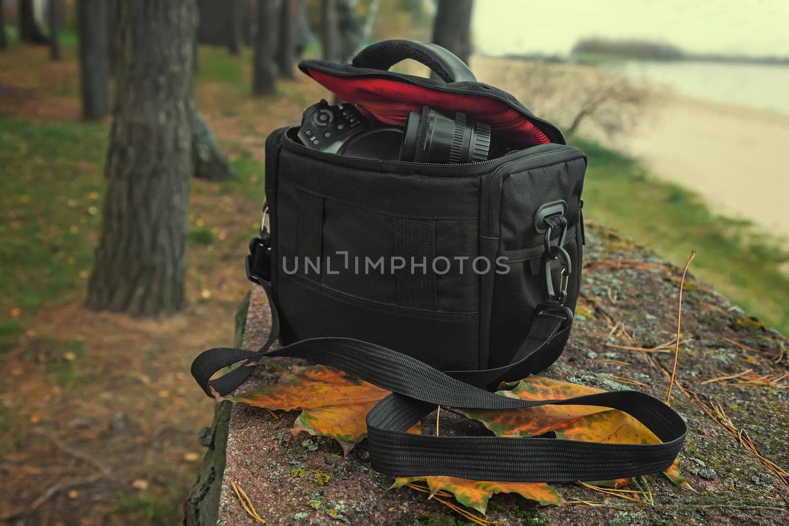 On the background of autumn Park by the river bag with camera and accessories for the photo shoot.