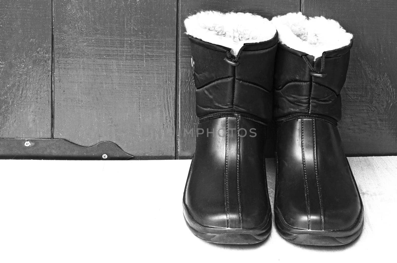 On the table near the wooden wall are warm waterproof men's boots for work or fishing.