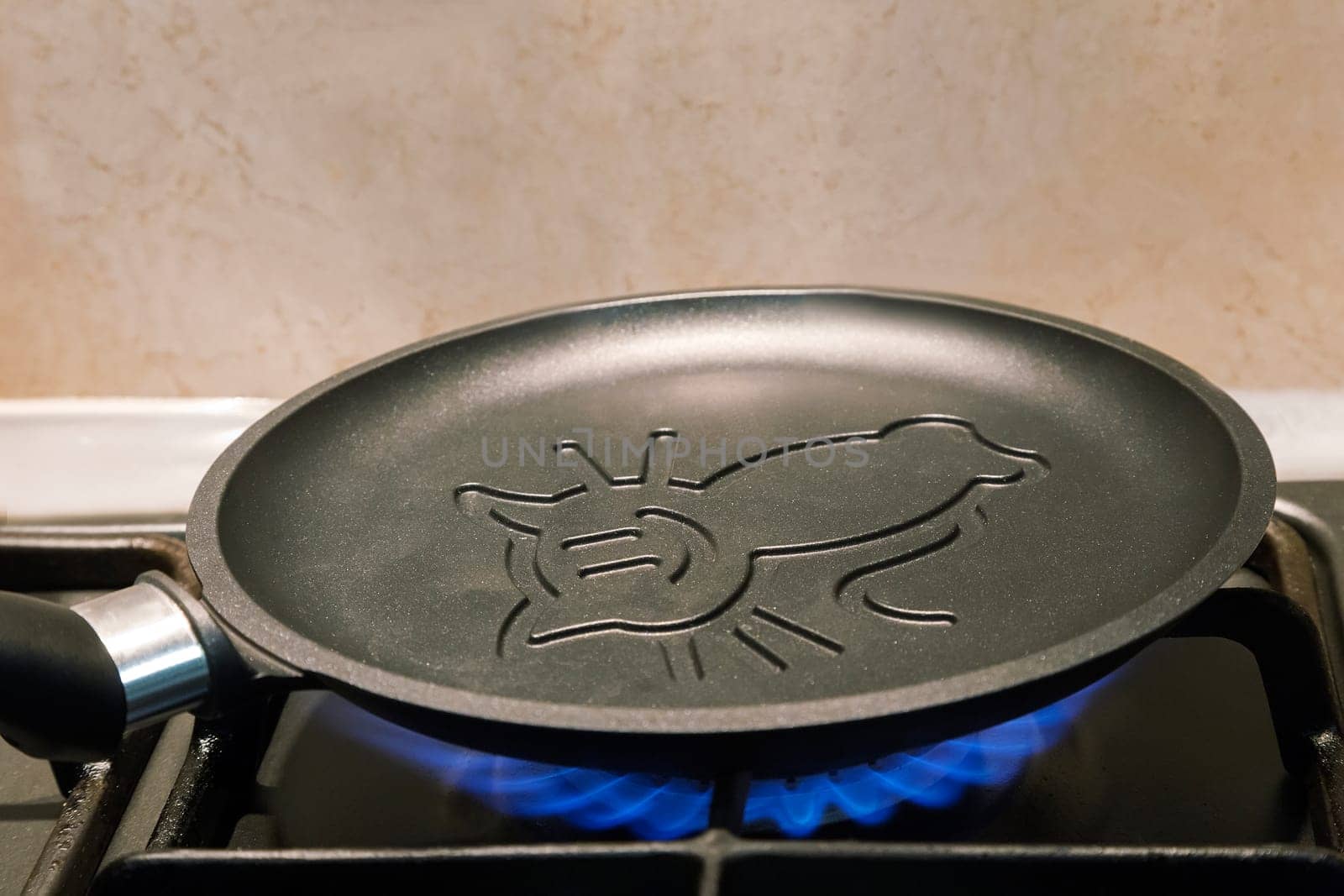 On fire of the gas stove heats up a cast iron frying pan for pancakes with ceramic coating.