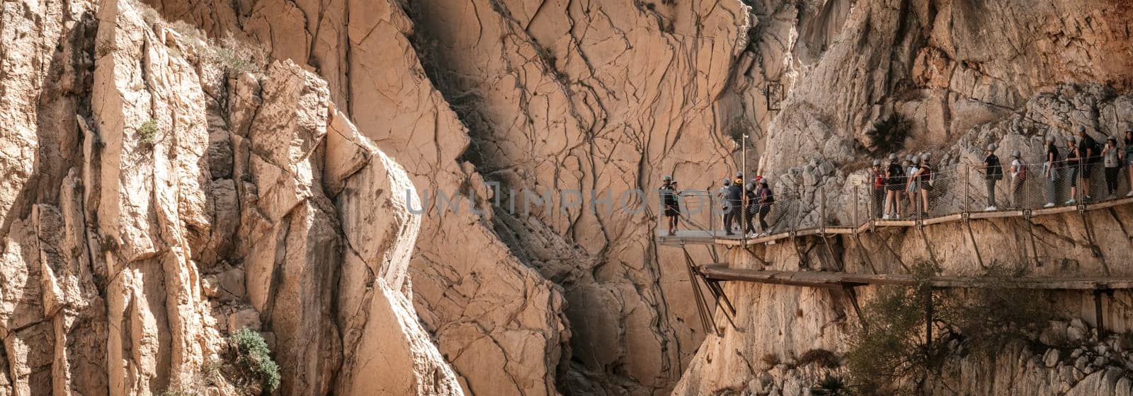 Tourists trek the awe-inspiring King's Pathway Canyon in Malaga, a vertiginous walkway hanging amidst vertical rock walls.