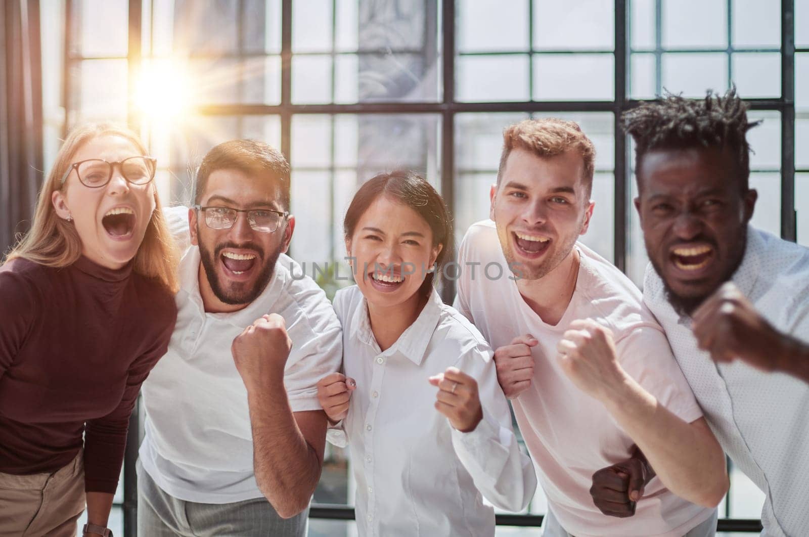 Group of mono-ethnic corporate employees clenching their fists celebrating success