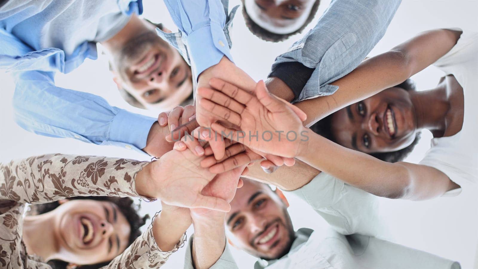 Closeup portrait, bottom view, happy faces of different team employees standing in circle, looking at camera, smiling business women and businessmen doing team building, posing for photo