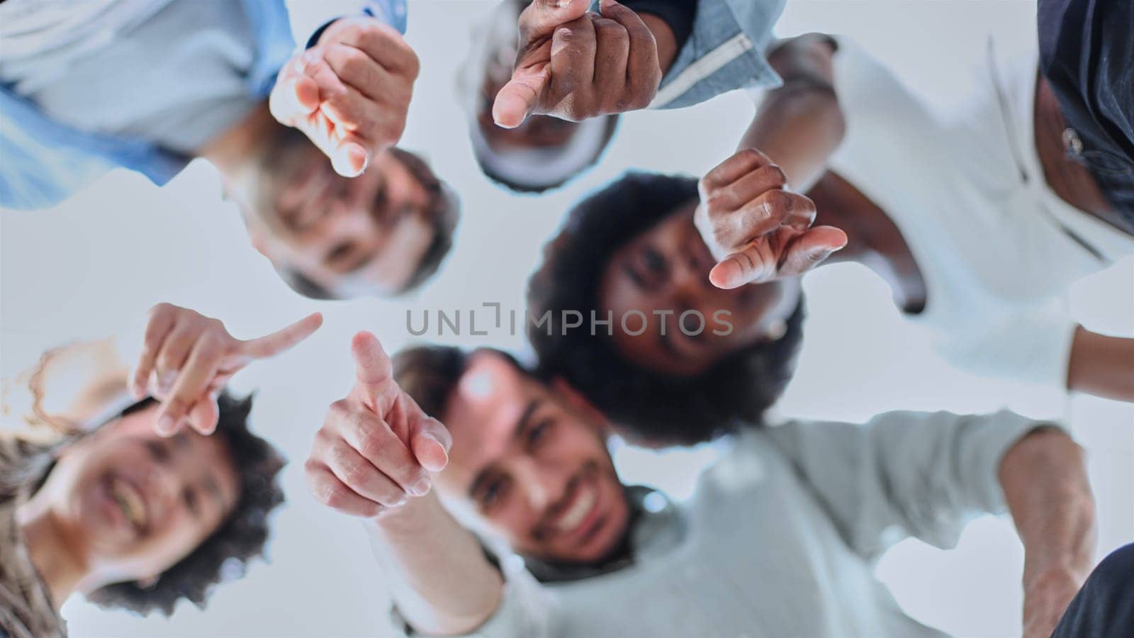 Closeup portrait, bottom view, happy faces of different team employees standing in circle, looking at camera, smiling business women and businessmen doing team building, posing for photo