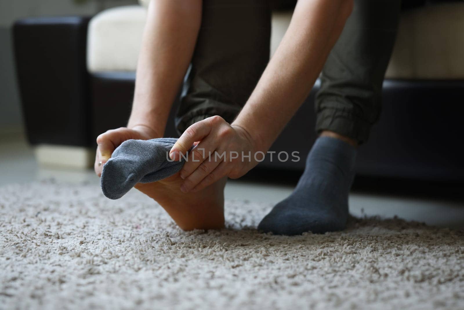 Man at home in morning puts gray socks on his leg. For a long time do not change clothes concept