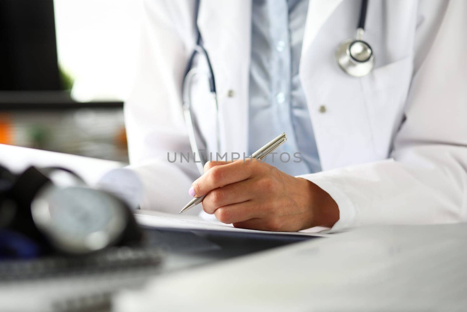 Hands of female GP making notes with silver pen by kuprevich