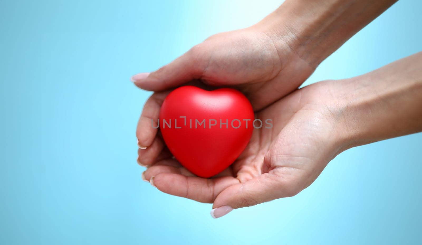 Woman hand hold red toy heart in hand closeup by kuprevich
