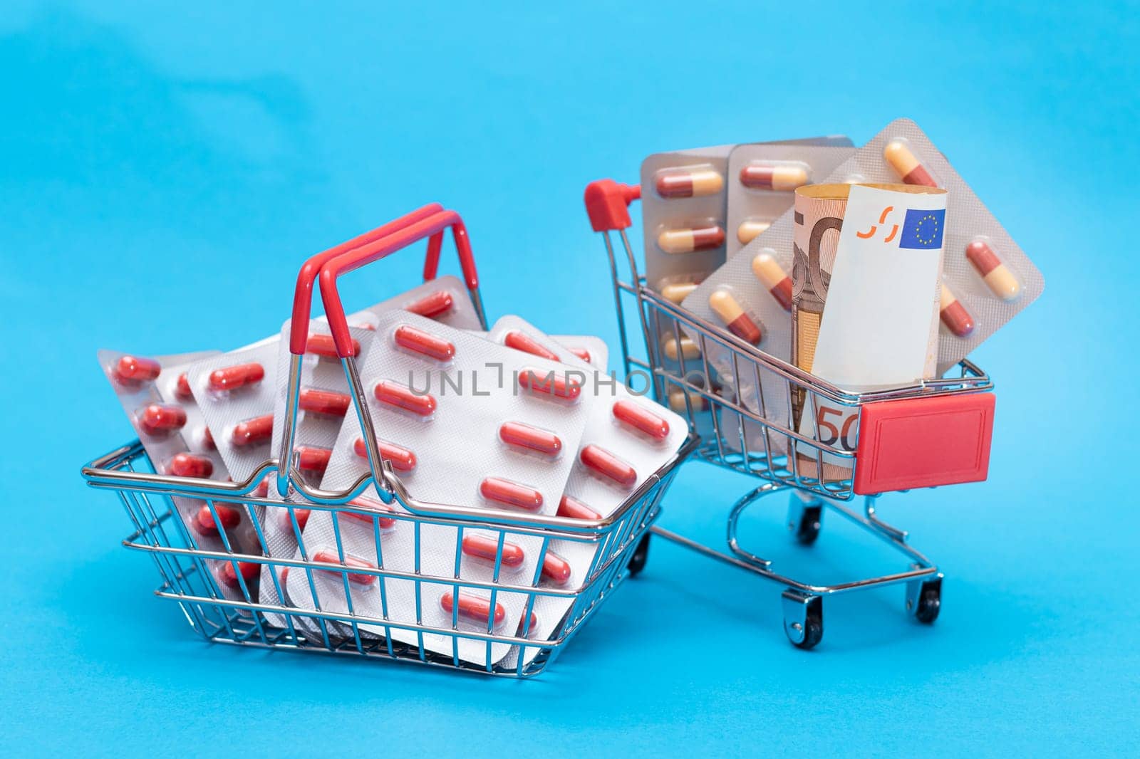 Pills and Capsules in Shopping Cart on Blue Background by InfinitumProdux