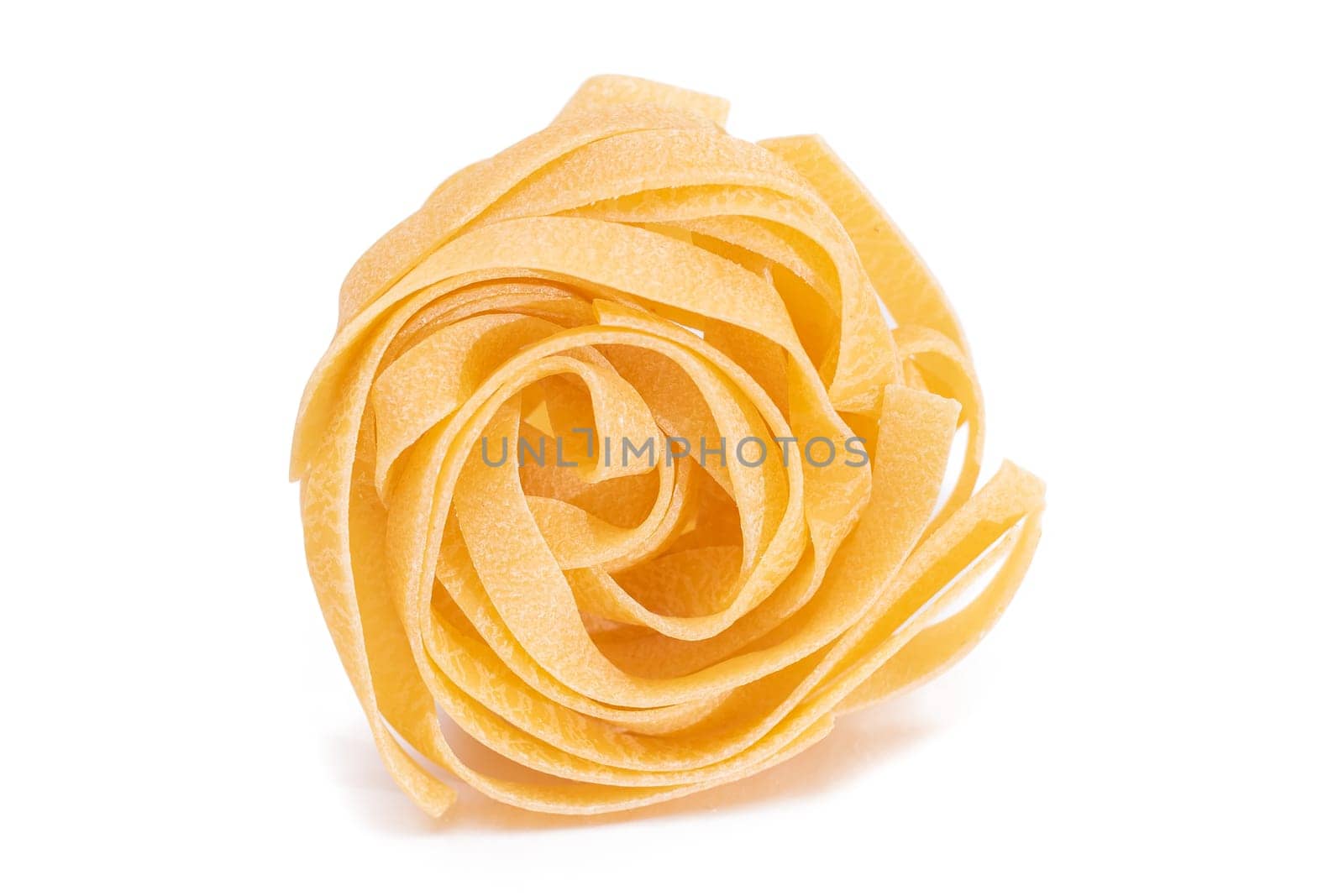One Classic Italian Raw Egg Fettuccine - Isolated on White Background. Dry Twisted Uncooked Pasta. Italian Culture and Cuisine. Raw Golden Macaroni Pattern - Isolation