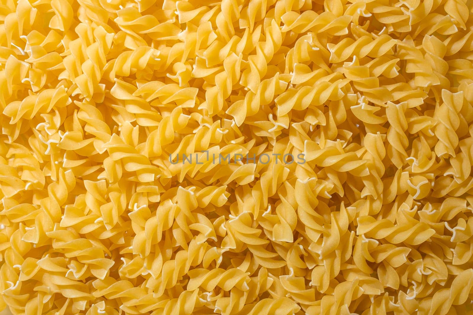 Uncooked Fusilli Pasta: A Culinary Canvas of Spiral Macaroni, Creating a Lively and Textured Background for Gourmet Cooking. Dry Pasta. Raw Macaroni - Top View, Flat Lay