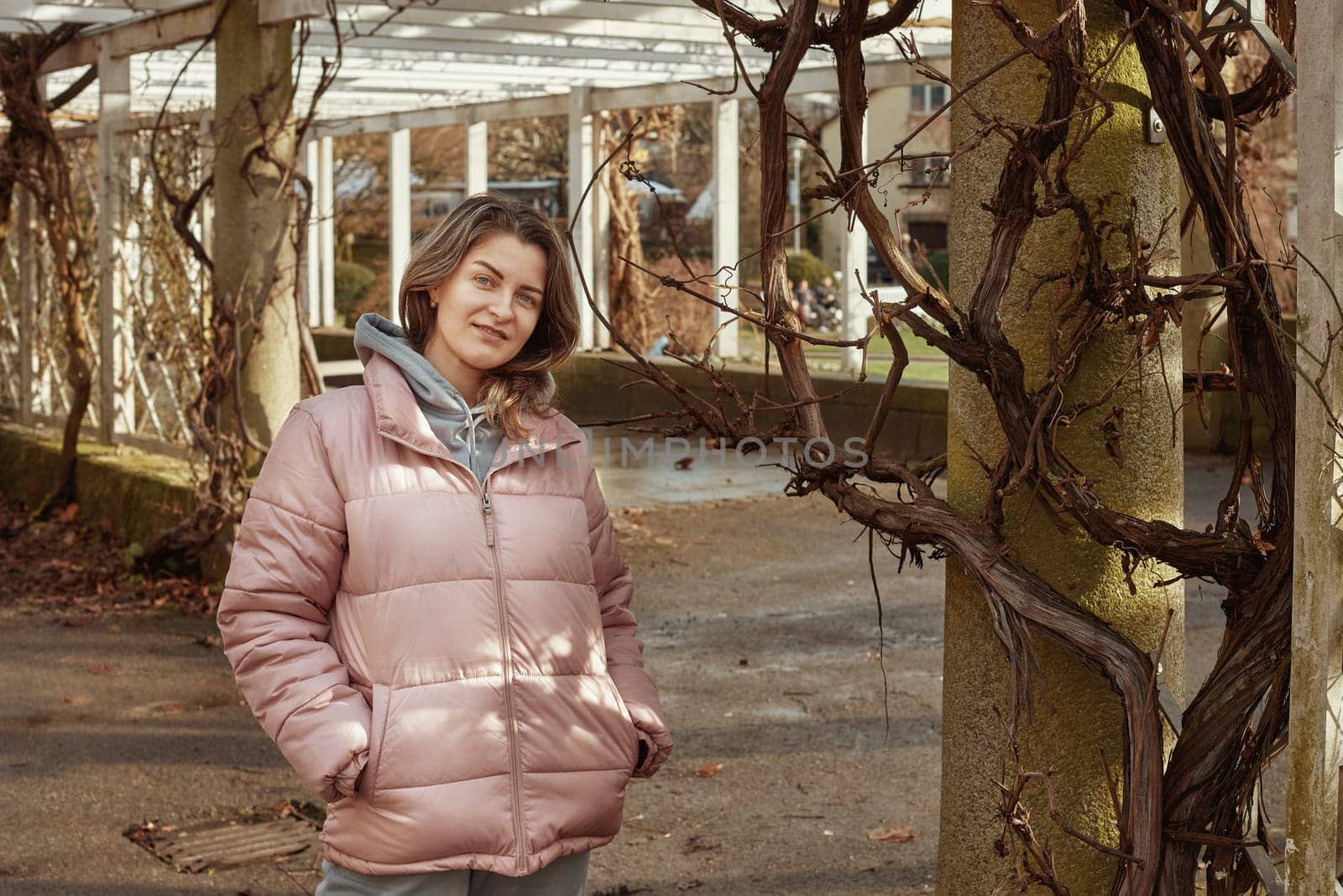 Young beautiful pretty tourist girl in warm hat and coat with backpack walking at cold autumn in Europe city enjoying her travel in Zurich Switzerland. Outdoor portrait of young tourist woman enjoying sightseeing