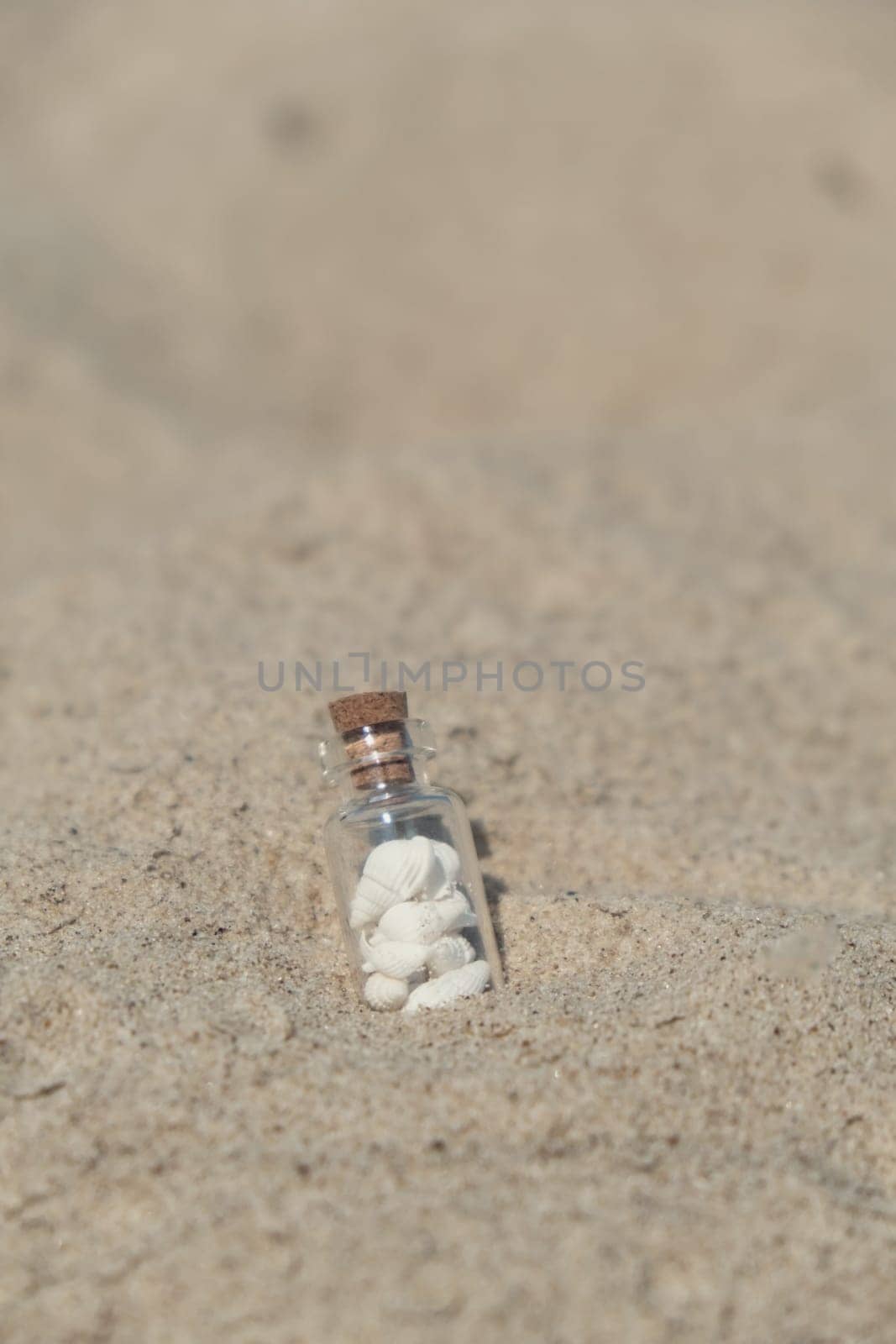 Souvenir Glass bottle with Sea shell. Seashell in glass bottle with seashells on the seashore sandy beach. Ocean seashell. Summer Memories from vacation Concept for travel agency