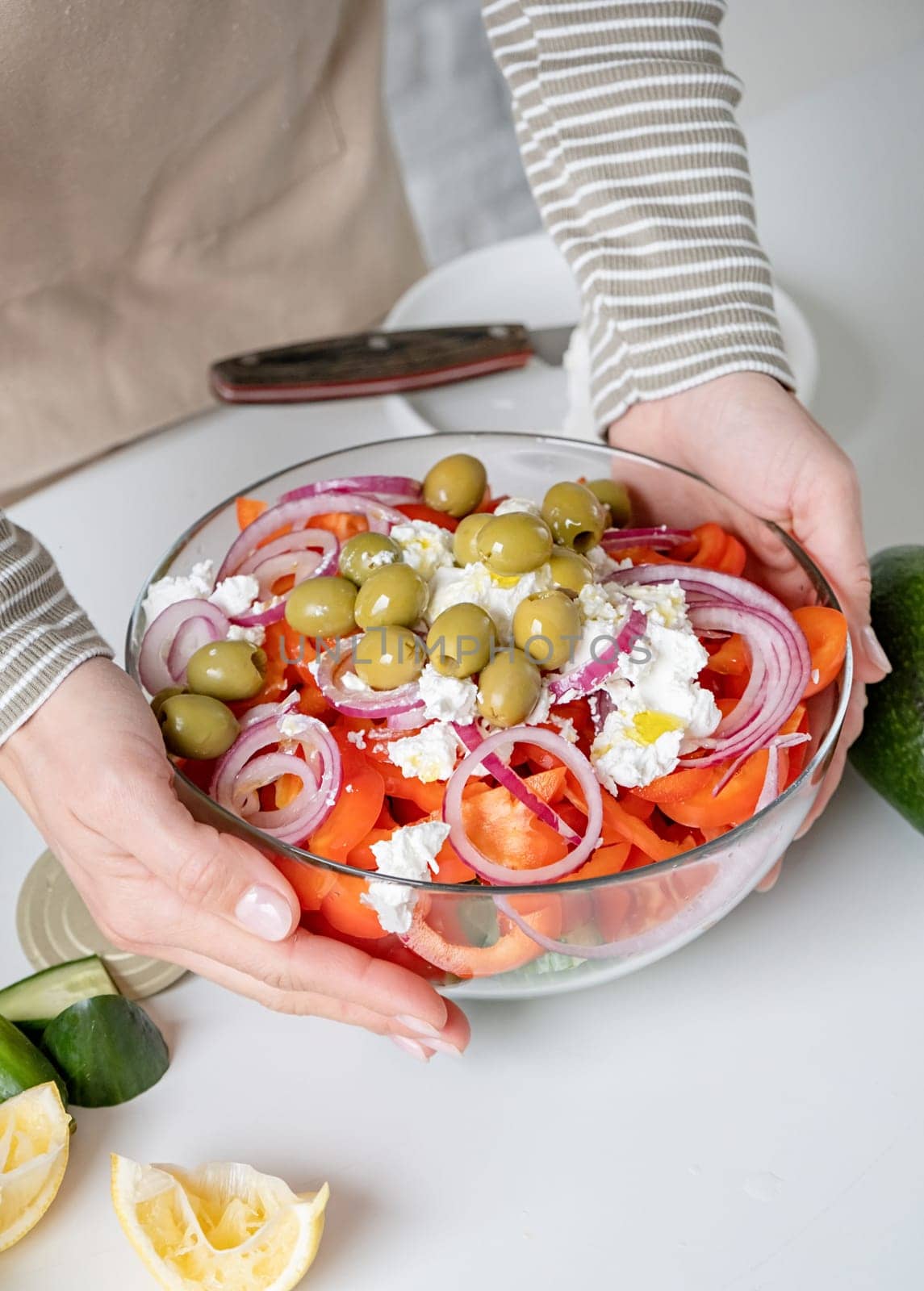 Cooking process of Greek Salad. Woman adding olives to bowl of Greek salad