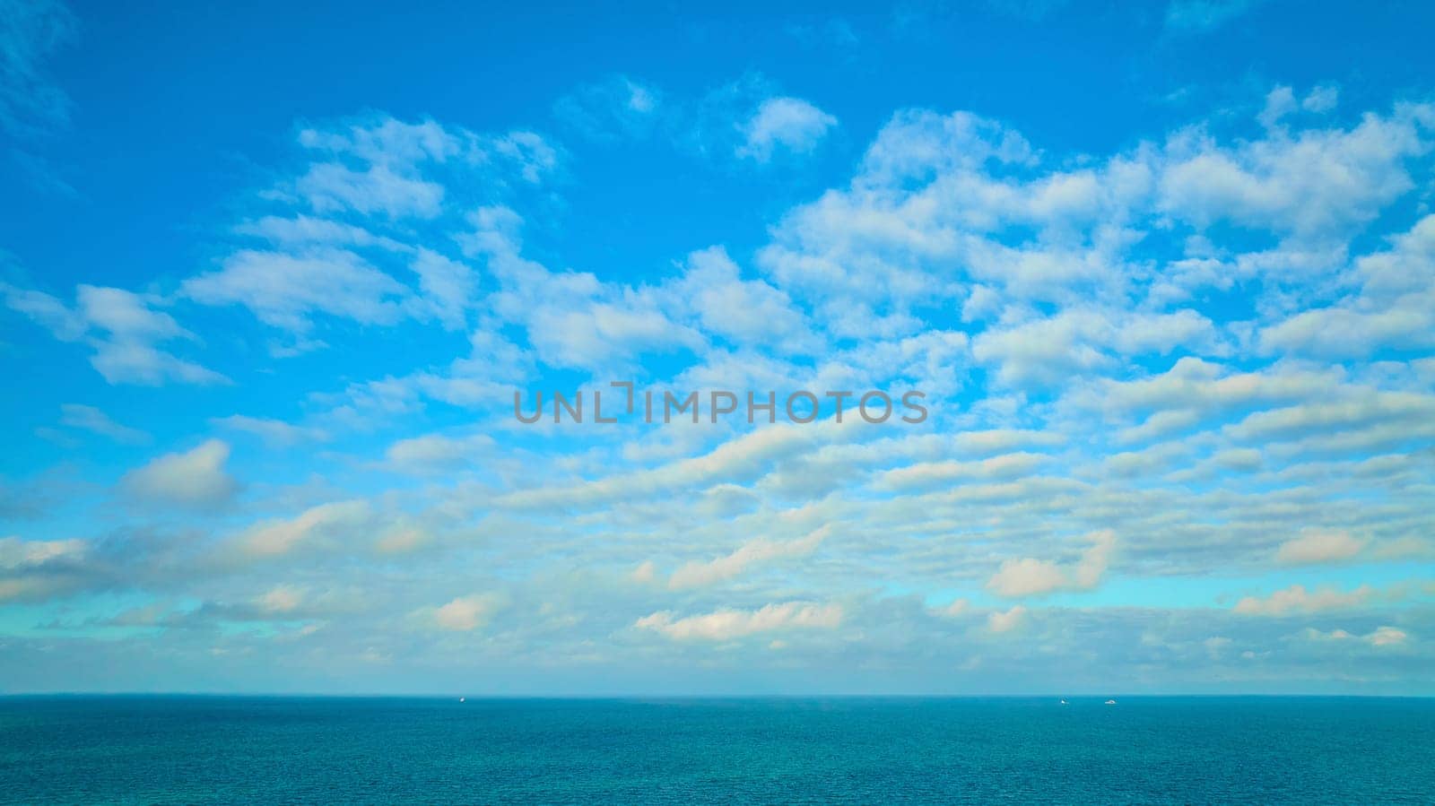 Image of Blue sky with wispy white clouds, dream and inspiration over blue Lake Michigan water, inspire