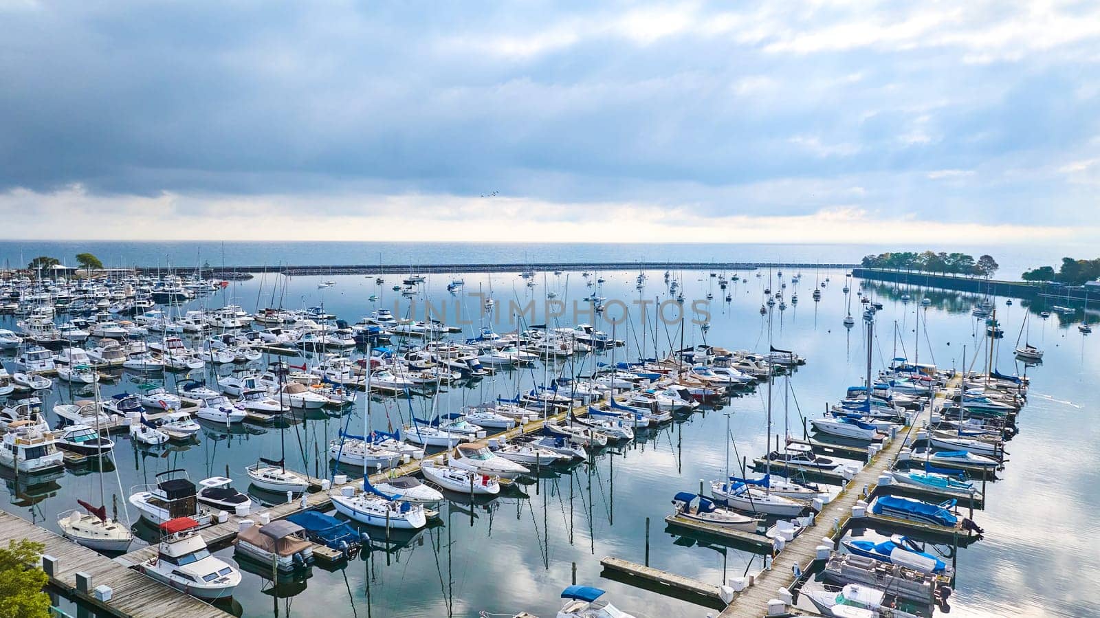 Aerial view of tranquil Lake Michigan marina in Milwaukee, showcasing an array of moored yachts captured by DJI Mavic 3 drone.
