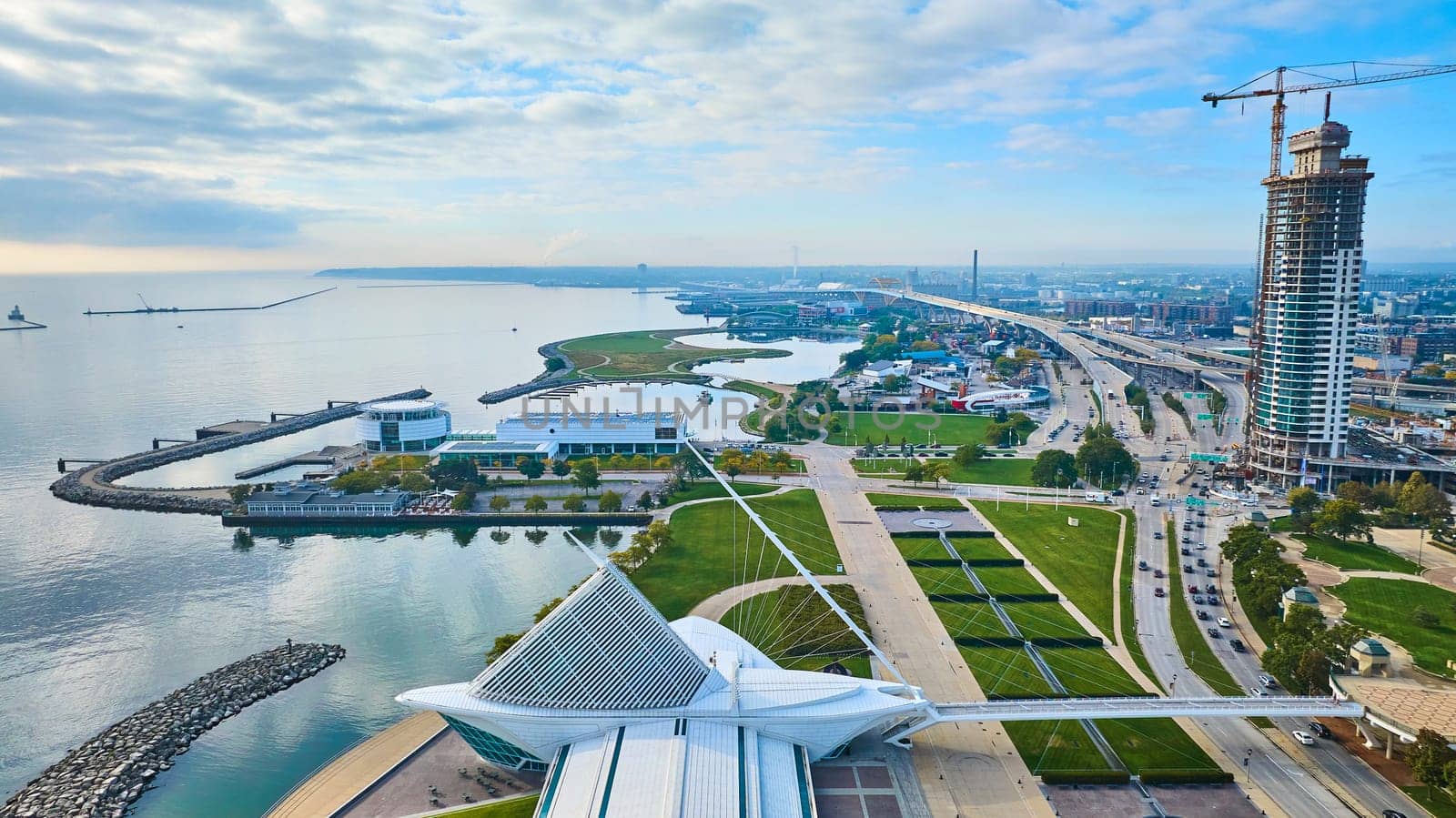 Aerial sunrise view of Milwaukee's iconic Quadracci Pavilion, bustling skyscraper construction, and serene Lake Michigan marina