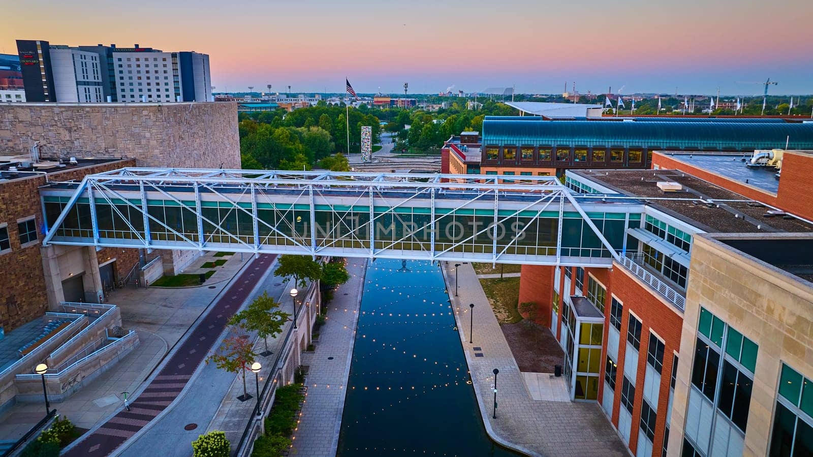 Serene aerial view of modern pedestrian bridge over tranquil canal during blue hour, downtown Indianapolis, 2023