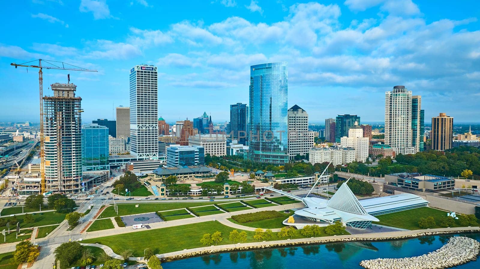 2023 Aerial View of Milwaukee Skyline, showcasing a blend of shiny skyscrapers, ongoing construction, and the iconic Quadracci Pavilion nestled in a green park, all captured by a DJI Mavic 3 drone.