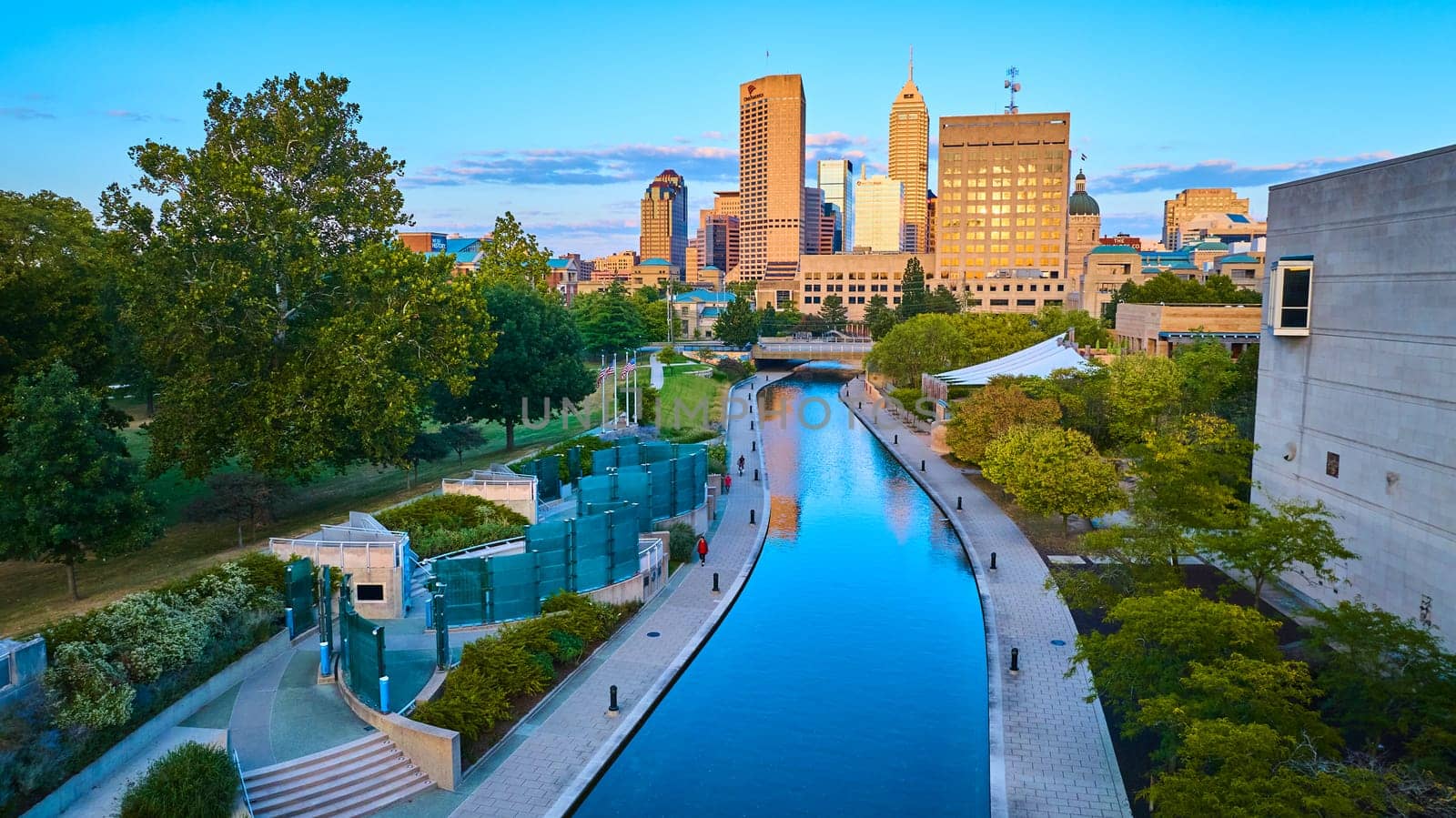 Golden Hour Over Indianapolis: Tranquil Canal Reflects Urban Skyline, Captured from Aerial View