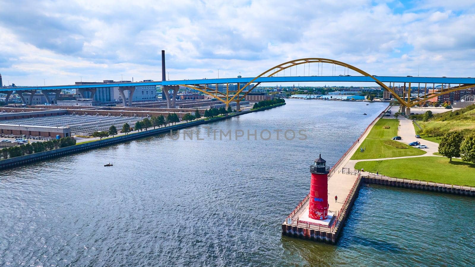Vibrant aerial view of Milwaukee's waterfront with the iconic red Pierhead Lighthouse, golden Daniel W. Hoan Memorial Bridge, and shimmering Lake Michigan