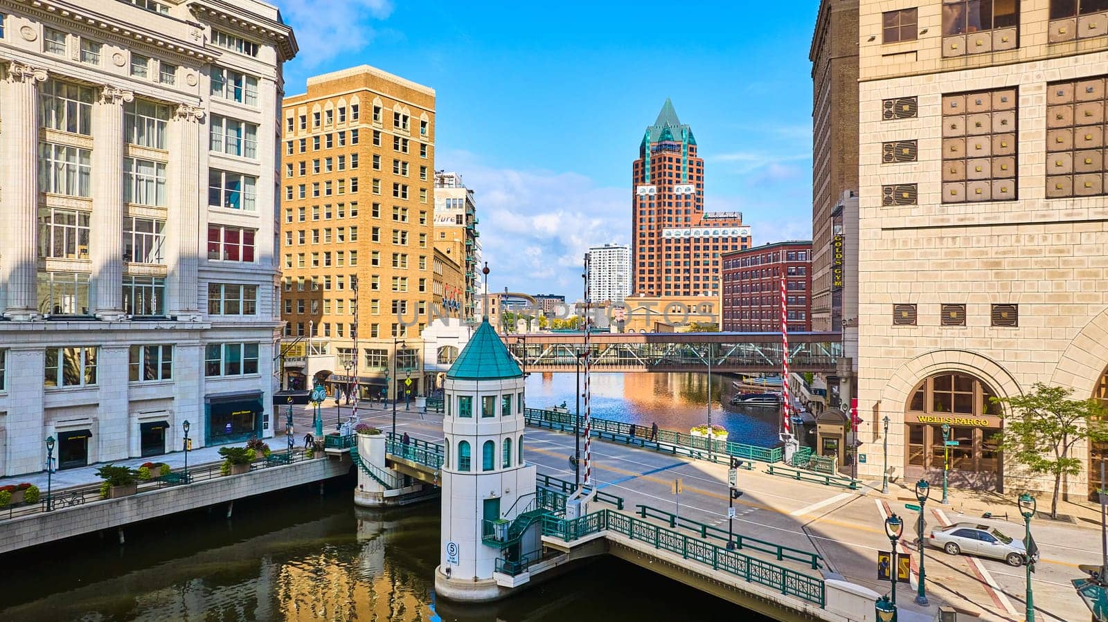 2023 drone view of Milwaukee, Wisconsin showcasing a bustling river scene with diverse architecture from a green-roofed skyscraper to a charming bridge house.
