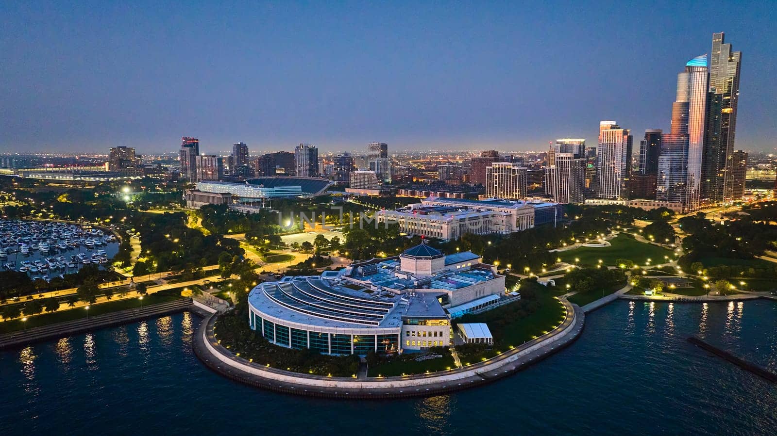 Shedd Aquarium aerial with city lights on Lake Michigan water at night and Chicago in background by njproductions