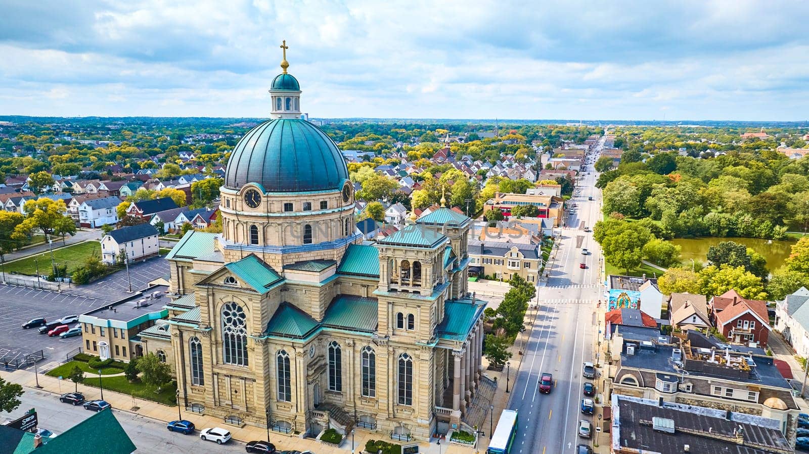 Aerial view of the historic Basilica of St Josaphat with its green patina roof, nestled in a serene Milwaukee suburb, captured by a DJI Mavic 3 drone.