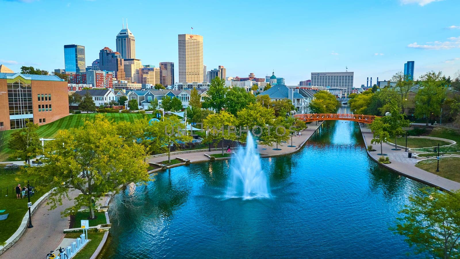 Vibrant Urban Park with Fountain and Orange Pedestrian Bridge against Indianapolis Skyline, Aerial View