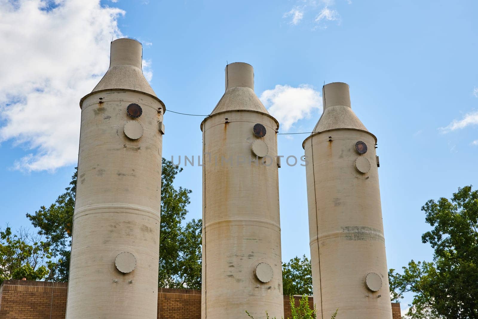 Daytime view of towering industrial silos in the Botanic Gardens of Elkhart, Indiana, showcasing robust infrastructure against a clear blue sky