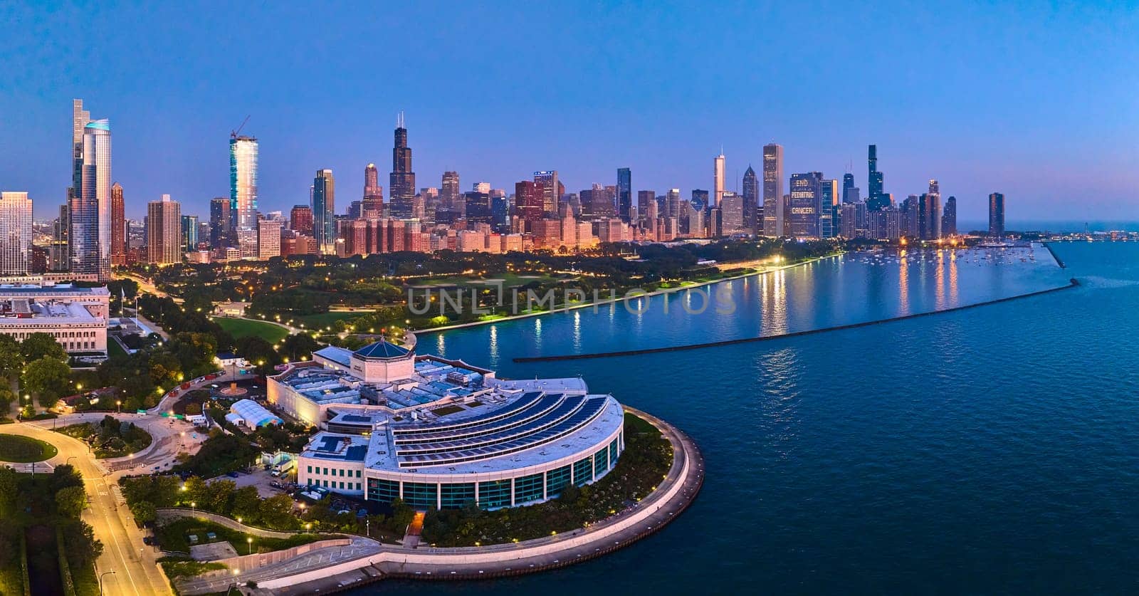 Vibrant Chicago skyline at dusk, featuring the iconic Willis Tower and Shedd Aquarium, captured by an aerial drone over Lake Michigan