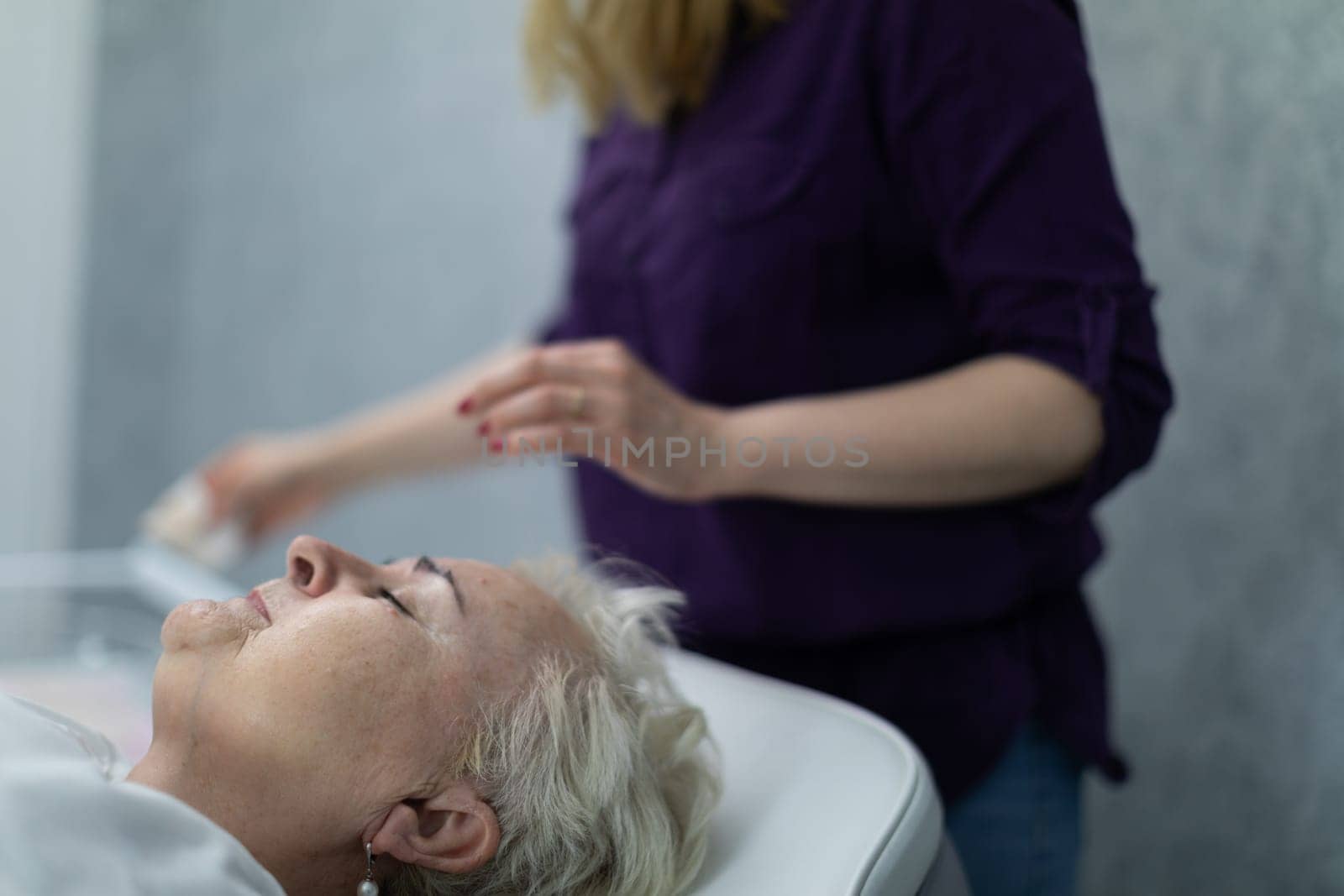 An elderly woman lies on a comfortable bed in a beauty salon by fotodrobik