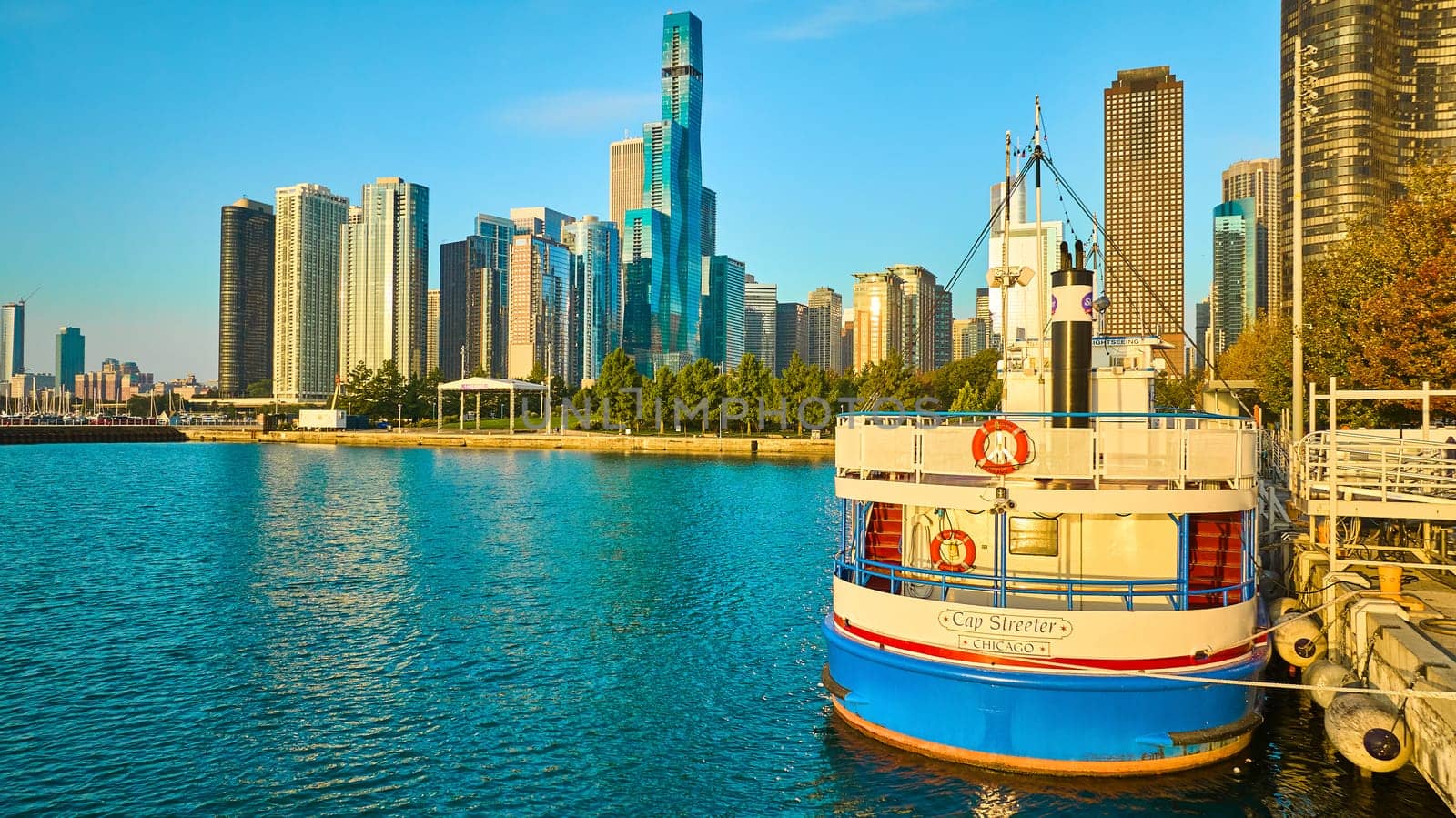 Aerial boat at Navy Pier at sunrise on Lake Michigan with downtown Chicago skyscrapers on coast by njproductions