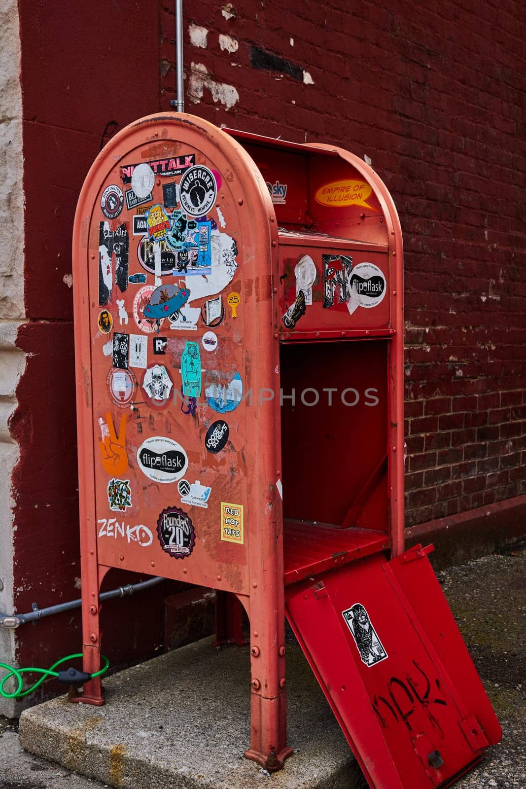 Vintage Red Mailbox Covered in Stickers Against Brick Wall by njproductions