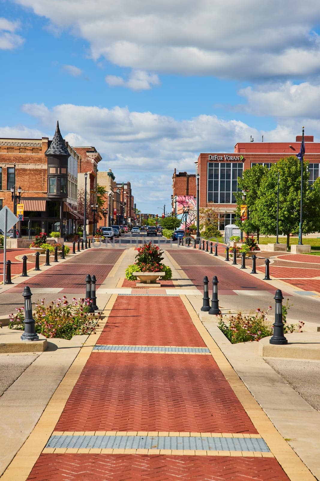 Daytime view of historic brick buildings, modern business, and pedestrian pathway in downtown Muncie, Indiana, showcasing small-town Americana in 2023.
