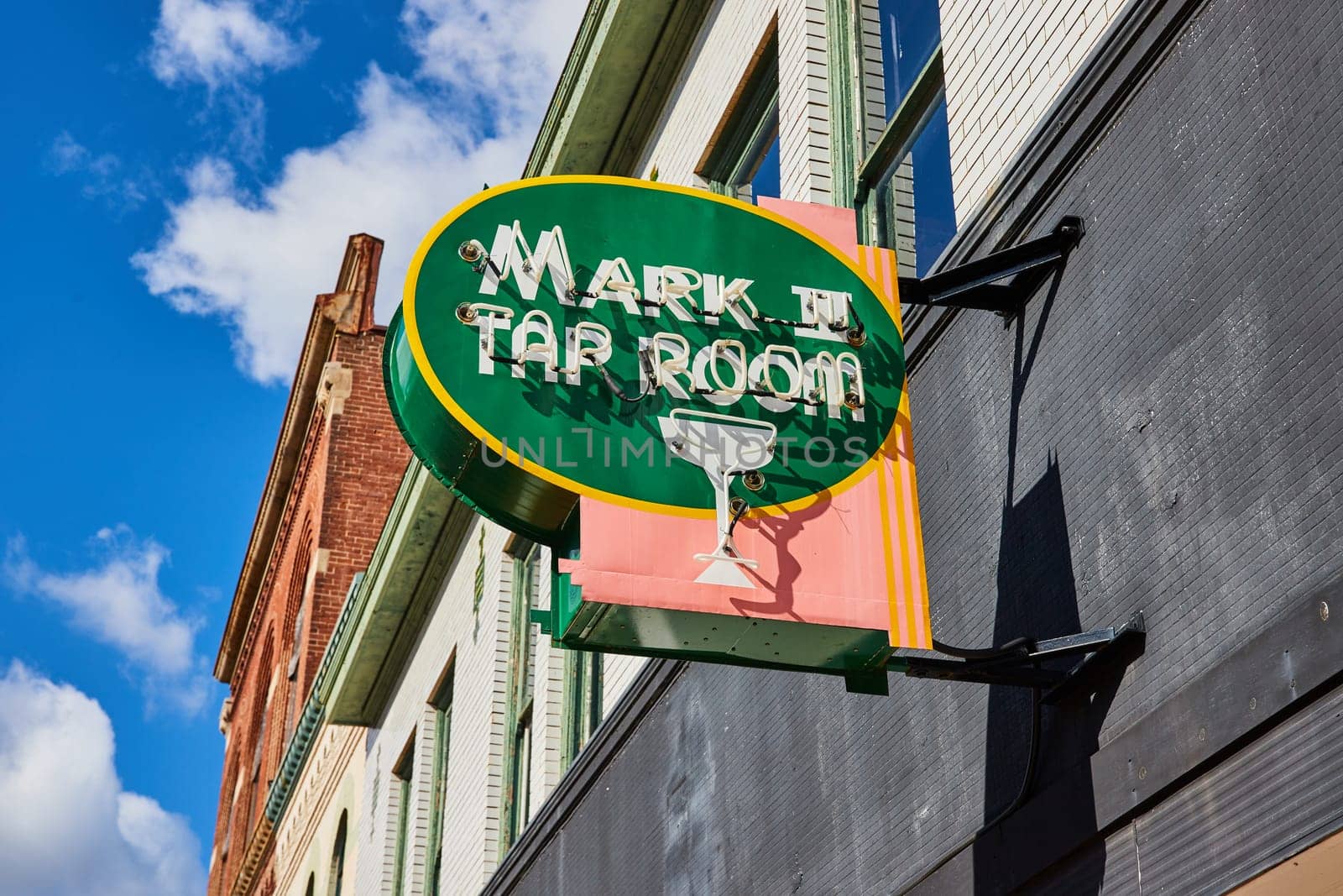 Retro-styled Mark II Tap Room sign under the clear blue sky in downtown Muncie, Indiana, showcasing local charm and vintage ambiance.