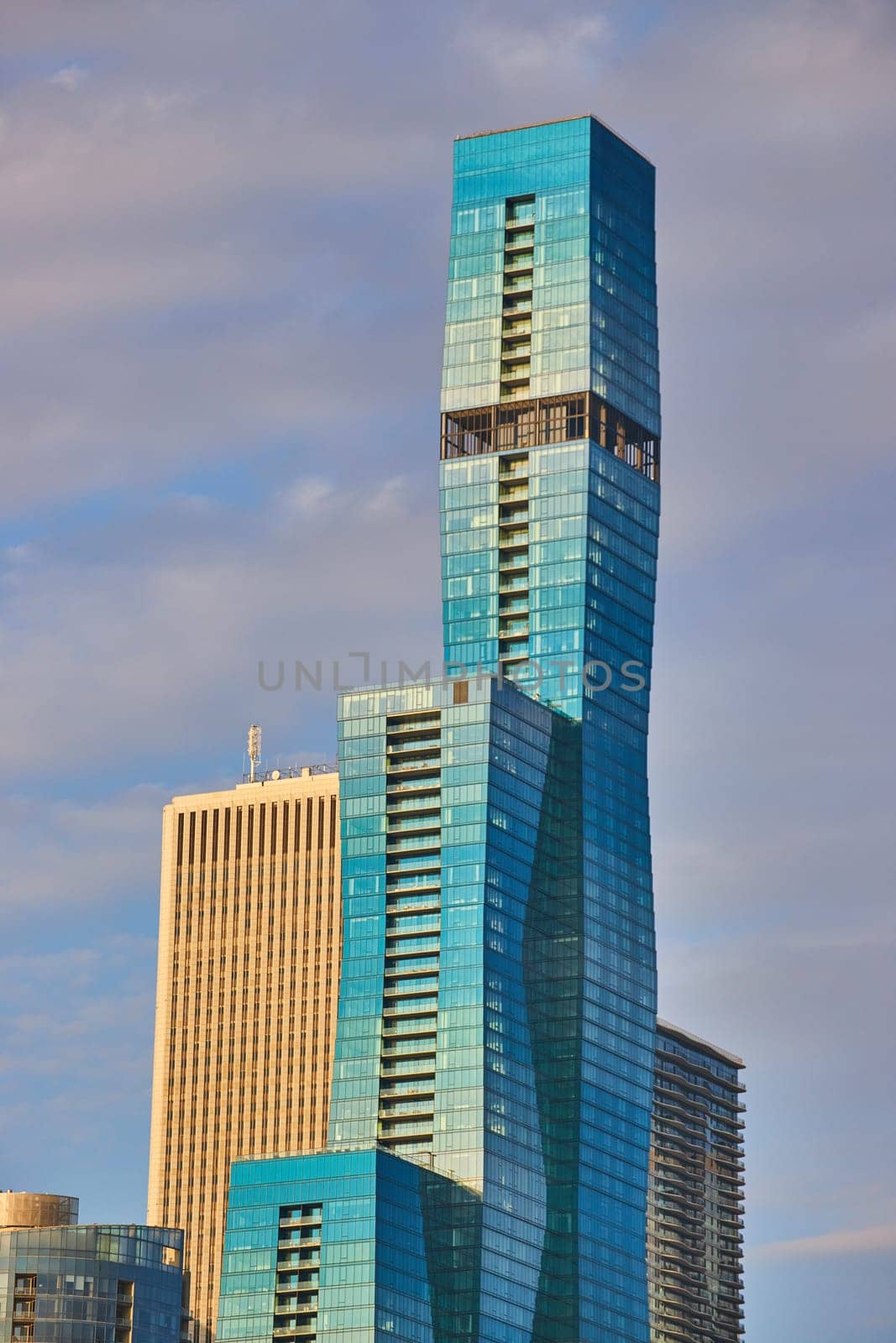 Blue skyscraper with multiple tiers in Chicago with golden light in summer and purple tinged sky by njproductions