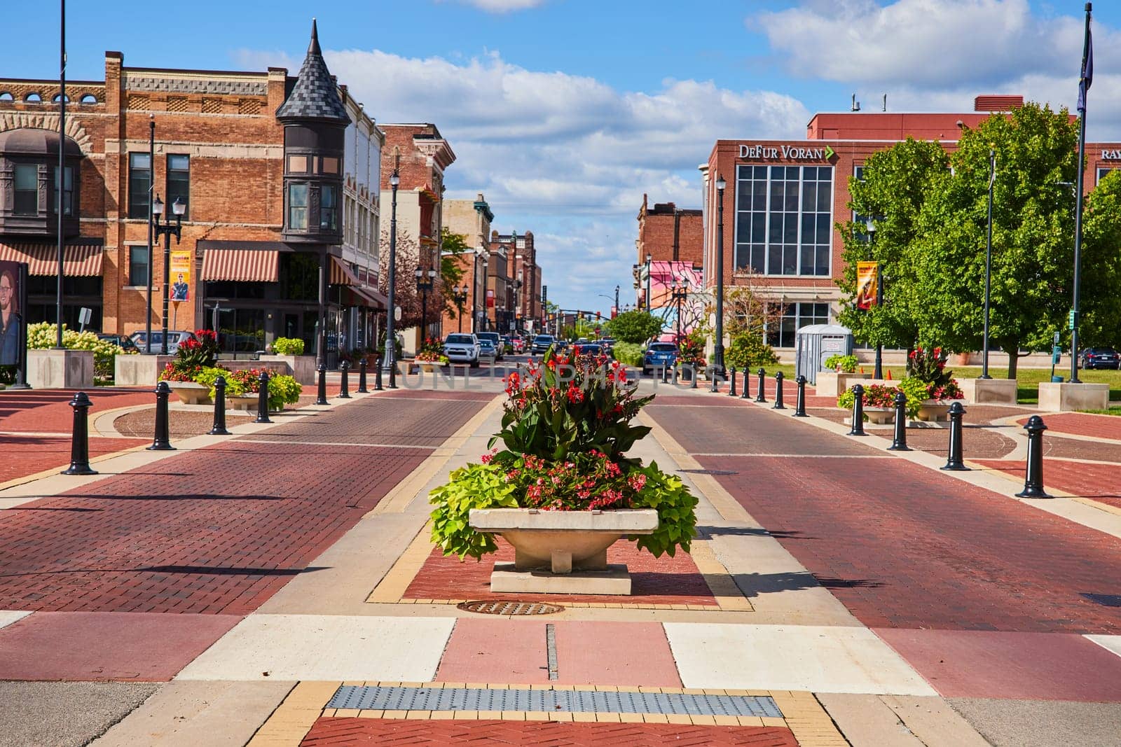 Downtown Muncie, Indiana in 2023: Vibrant flower planters enhancing pedestrian walkway amid historic and modern buildings.
