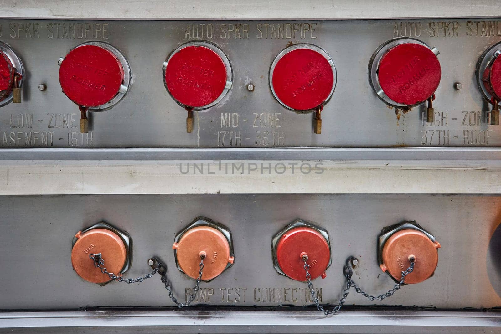 Image of Metal with six red caps for standpipe and copper caps on chains plugging up pump test connection