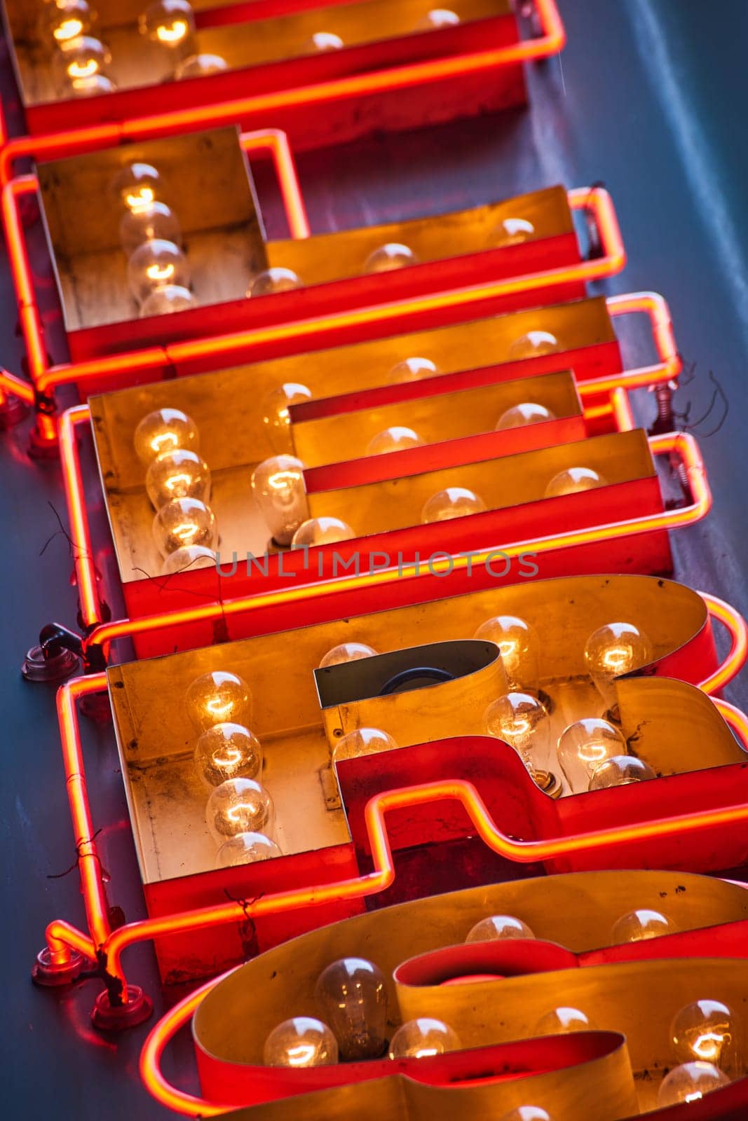 Image of Letters of sign close up in abstract view of antique, yellow lightbulb sign with orange tube lights