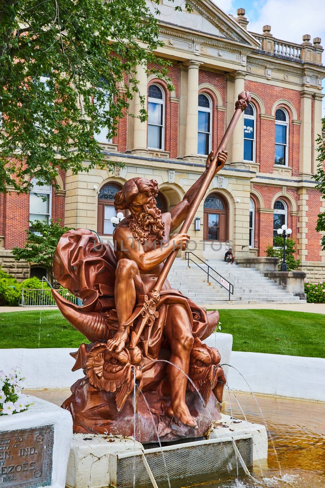 Poseidon bronze statue in yellow fountain at Elkhart County courthouse on summer day, law and order by njproductions